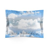 Standard pillow sham printed with fluffy white clouds on a blue and gray ombré sky background.