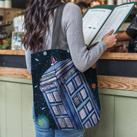Police call box floating in the solar system tote bag hanging on the shoulder of a woman at a restaurant counter.